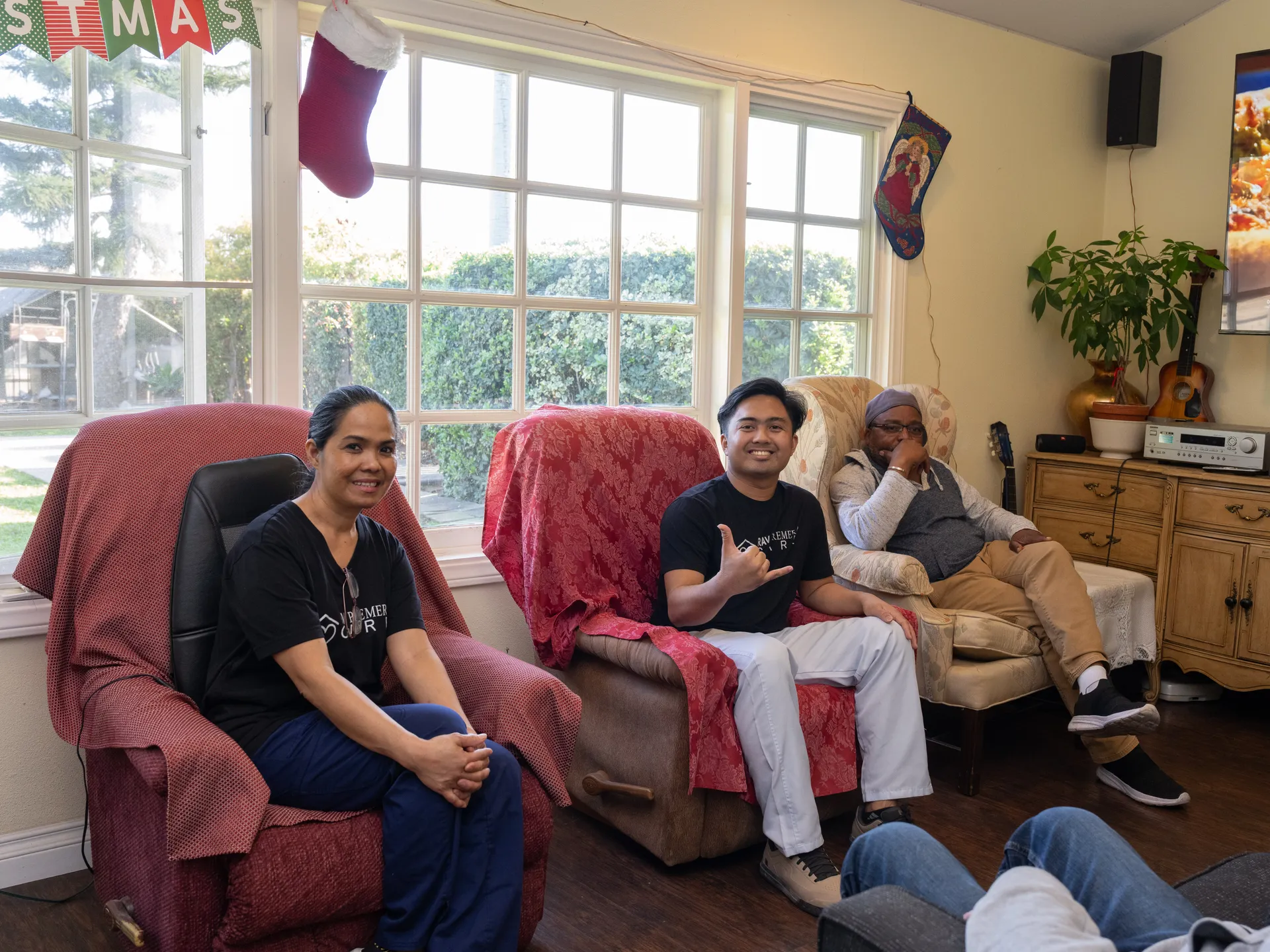 Three residents sitting together in a sunny living room decorated for the holidays