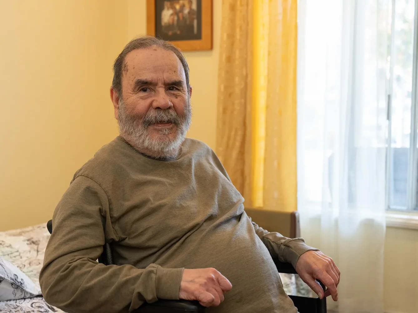 Senior male resident smiling while seated in his residential care facility room